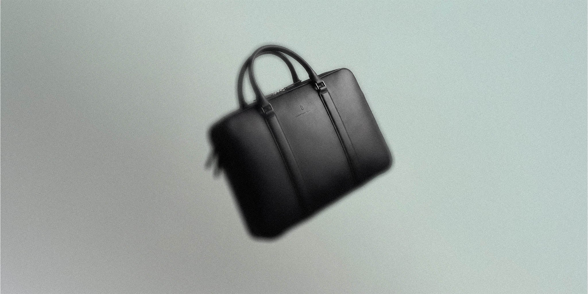 Black leather briefcase with double handles on a light background, modern minimalist design