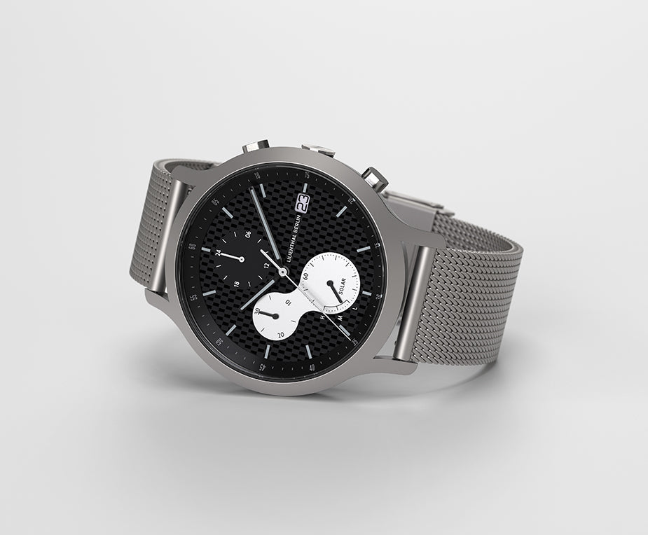 Silver mesh band chronograph watch with black textured dial, date display, and subdials