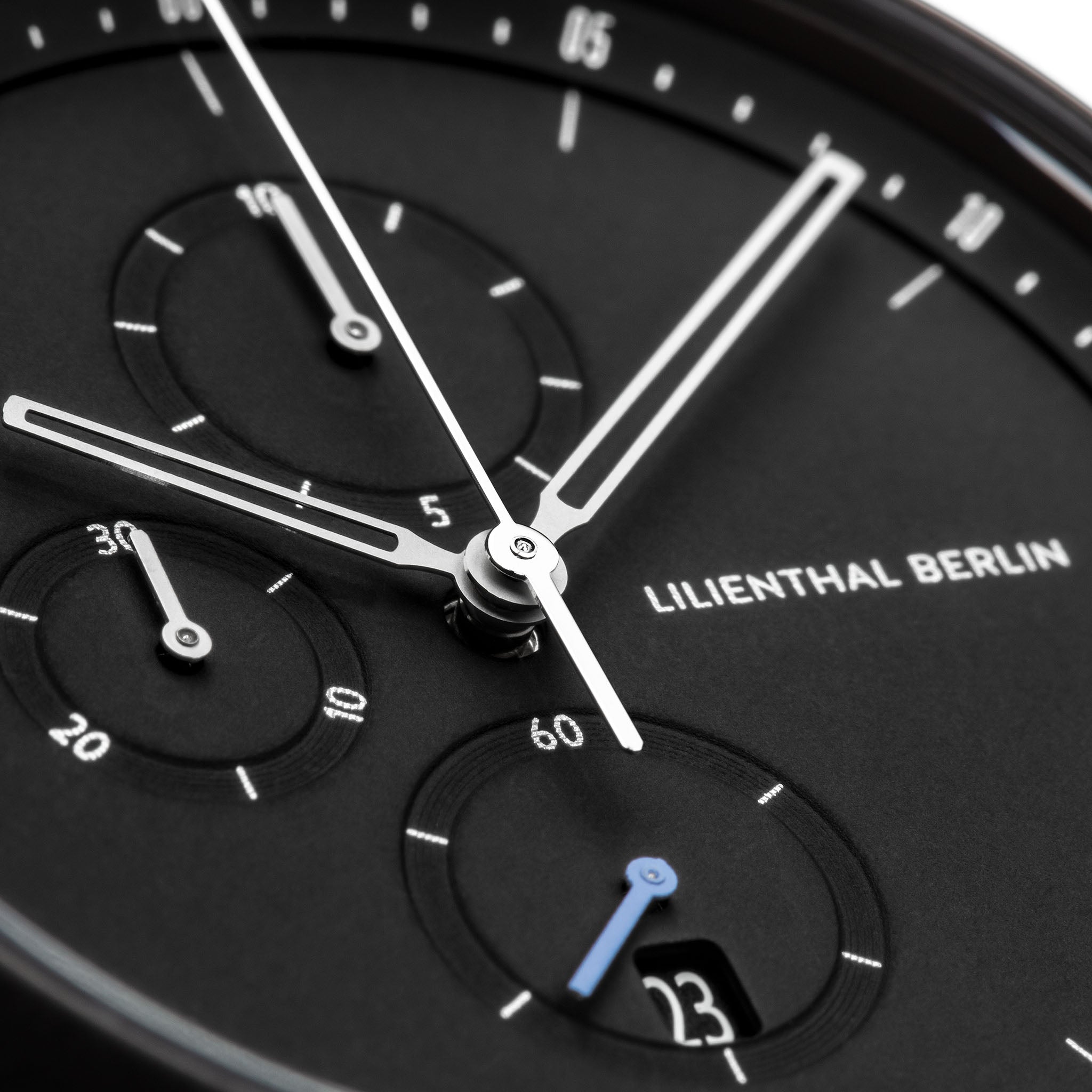 Close-up of modern black chronograph watch face with subdials and date display.