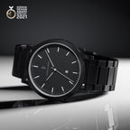 Minimalist black wristwatch with metal band, date display, and German Design Award 2021 badge